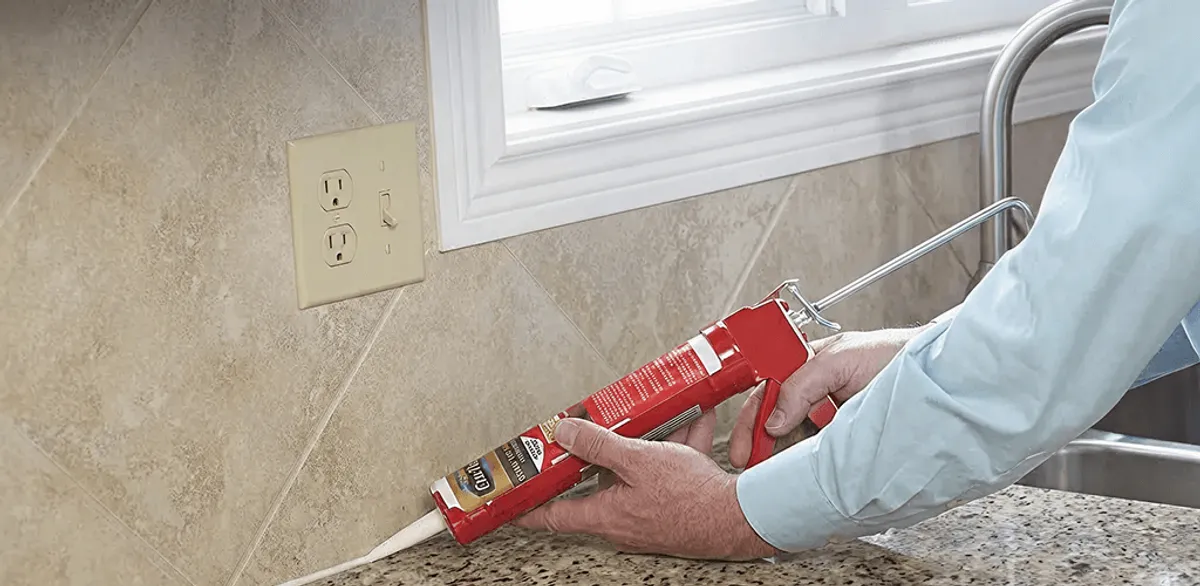 Handyman applying caulk along a kitchen backsplash and countertop seam in Phoenix, AZ